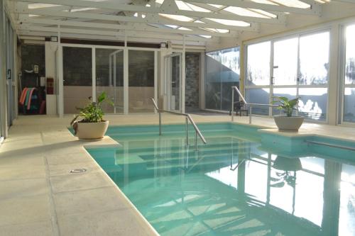 Una piscina con agua azul y plantas en un edificio. en Apart IMEB spa & wellness, en Río Cuarto