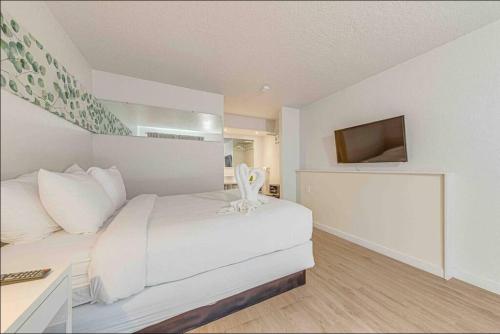 ein Schlafzimmer mit einem weißen Bett und einem Fernseher in der Unterkunft Travel Lodge by Wyndham 10 min from Disney in Kissimmee