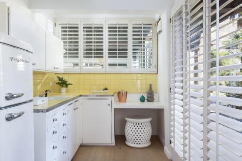 a white kitchen with white cabinets and yellow tiles at Del Marcos Hotel, A Kirkwood Collection Hotel in Palm Springs