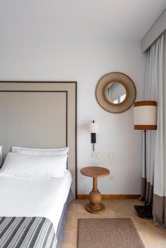 a bedroom with a bed and a mirror and a table at Parador de Mazagón in Mazagón
