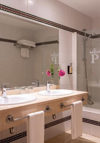 a bathroom with two sinks and a large mirror at Parador de Mazagón in Mazagón