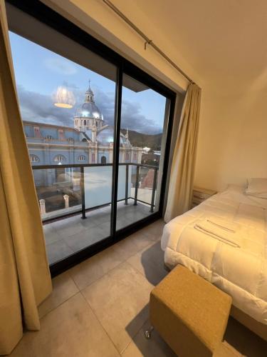 een slaapkamer met een bed en een groot raam bij Apartamento Mirador de la Viña. in Salta