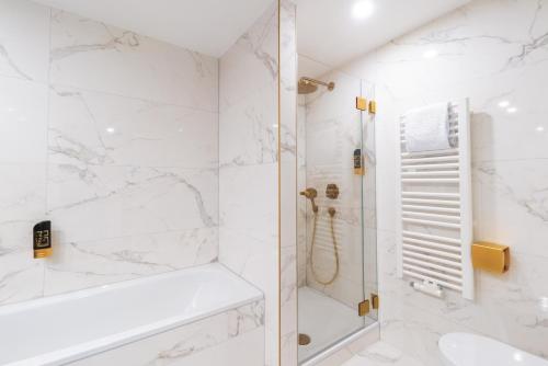 a white bathroom with a shower and a sink at Hotel Suitess in Dresden