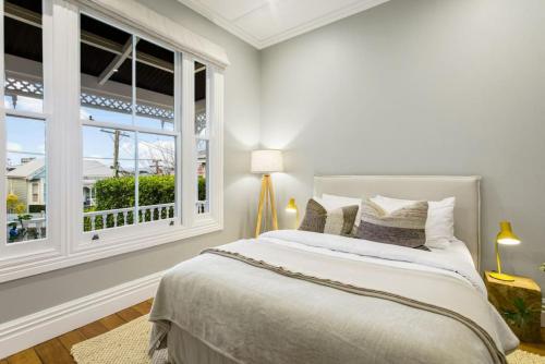 a white bedroom with a bed and a window at Luxury Executive Family Home with Parking & Spa in Auckland