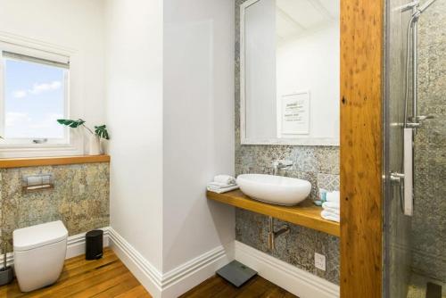 a bathroom with a sink and a toilet at Luxury Executive Family Home with Parking & Spa in Auckland