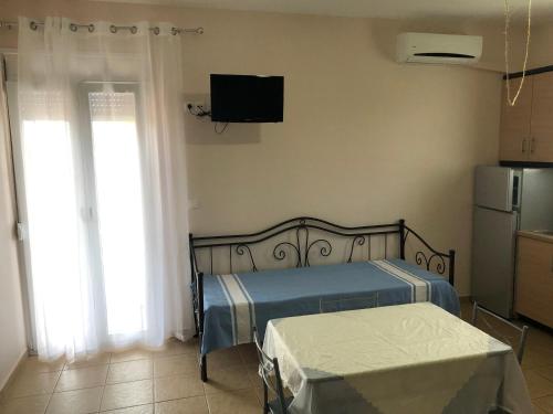 a bedroom with a bed and a television on the wall at Akrogiali studios in Vasiliká