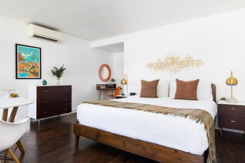 a bedroom with a large white bed with a chandelier at Del Marcos Hotel in Palm Springs