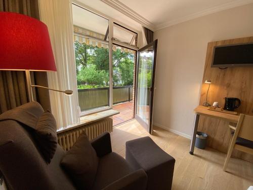 a living room with a couch and a large window at Hotel Sonnenhügel in Bad Bevensen