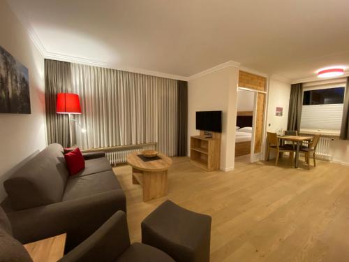 a living room with a couch and a room with a bed at Hotel Sonnenhügel in Bad Bevensen