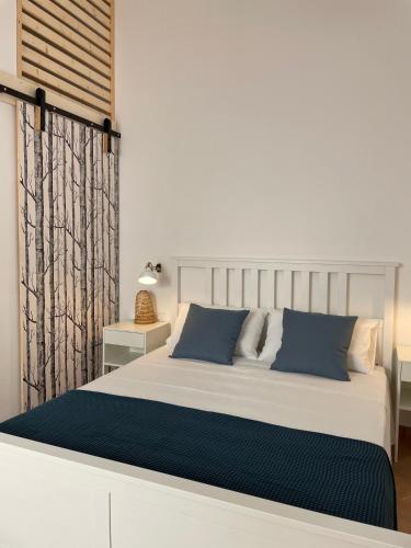 białe łóżko z niebieskimi poduszkami w sypialni w obiekcie A'mmare Rooms&Apartments Santa Maria di Leuca w mieście Leuca