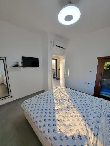a white bedroom with a bed with a blue comforter at קסם היסוד in Yesod Hamaala
