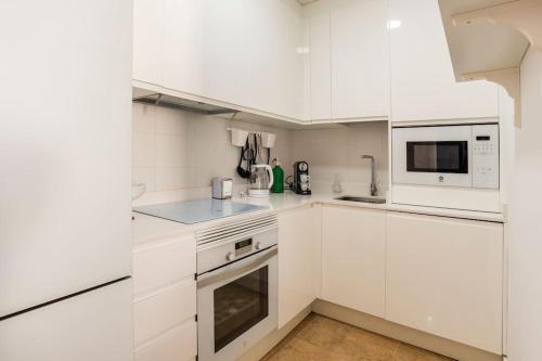 eine weiße Küche mit weißen Schränken und Geräten in der Unterkunft Apartamento Torremolinos centro in Torremolinos
