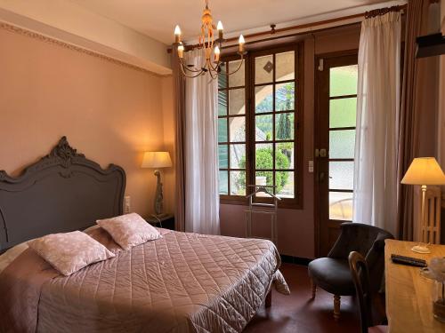 a bedroom with a bed and a window and a chair at Hôtel du Moulin in Allemagne-en-Provence