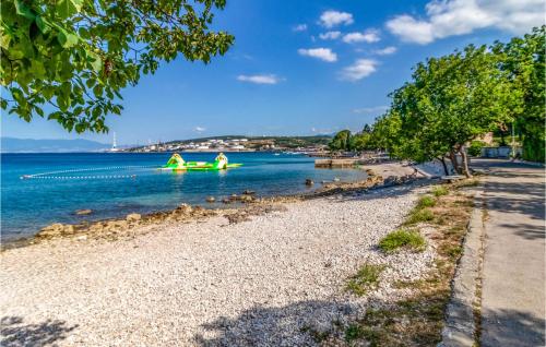 a beach with a green boat in the water at 3 Bedroom Amazing Home In Kraljevica in Kraljevica