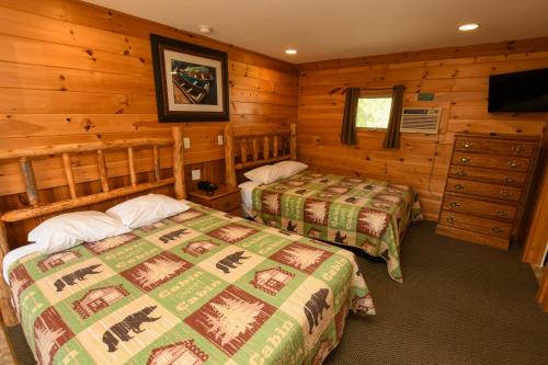 a bedroom with two beds in a log cabin at Lake George Diamond Cove Cottages, Cabins, & Hotel in Lake George