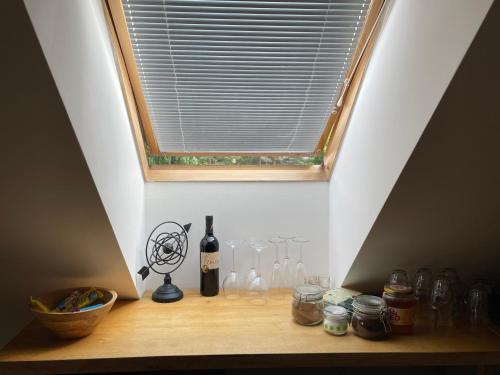a shelf with wine bottles and glasses under a window at Apartmány Polská 12 in Olomouc