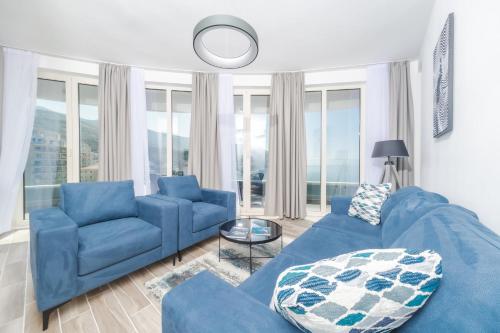 a blue couch and chairs in a living room with windows at Skyline Vista in Bečići