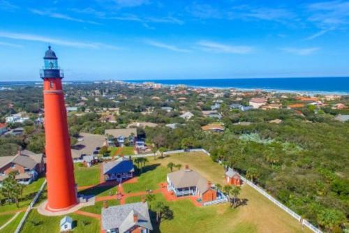 an aerial view of a red lighthouse with a house at Coastline Penthouse Condo in Daytona Beach Shores