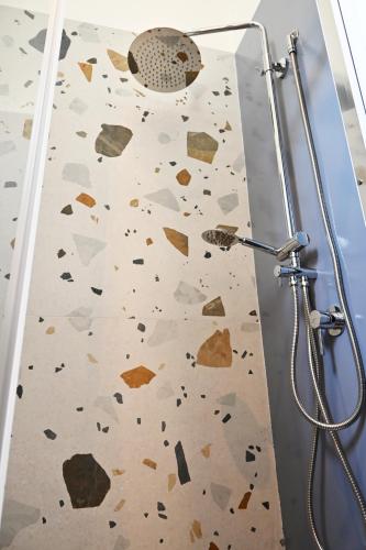 a bathroom with a shower with a wall covered in rocks at Mimosa e Agave Blu in Scicli
