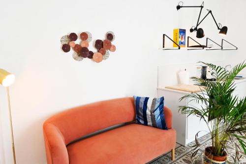 an orange couch in a living room with a plant at Mimosa e Agave Blu in Scicli