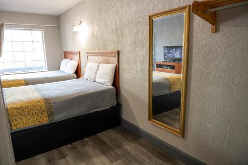 a small room with two beds and a mirror at Riverside Inn and Suites in Hopewell