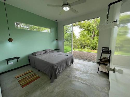 een slaapkamer met een bed en een groot raam bij Green House in Puntarenas