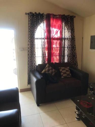 a living room with a black couch in front of a window at Leila VIllage Plus in Mendes