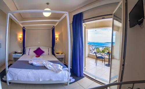 a bedroom with a bed and a balcony with the ocean at Thea Hotel - Studios & Suites in Marmarion
