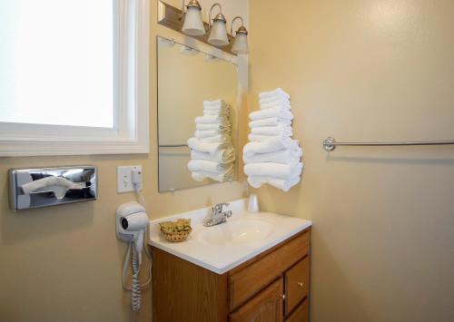 a bathroom with a sink and a mirror and towels at Charm Motel & Suites in Burney