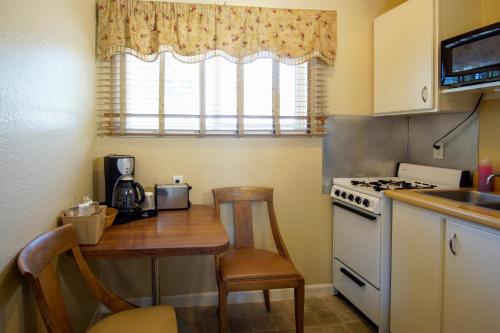 a kitchen with a table and a stove and a window at Charm Motel & Suites in Burney