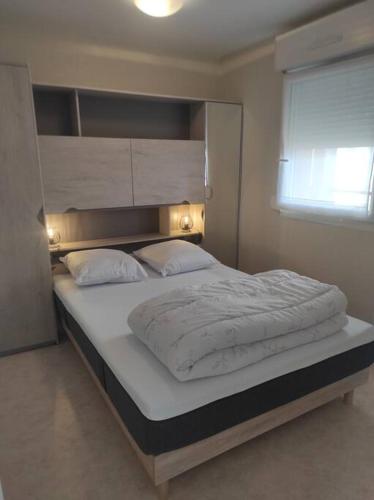 une chambre avec un grand lit avec des draps et des oreillers blancs dans l'établissement L'Albatros 15, à Fort-Mahon-Plage