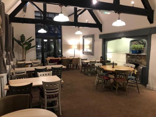 a dining room with tables and chairs and lights at Shenstone Lodge in Kidderminster