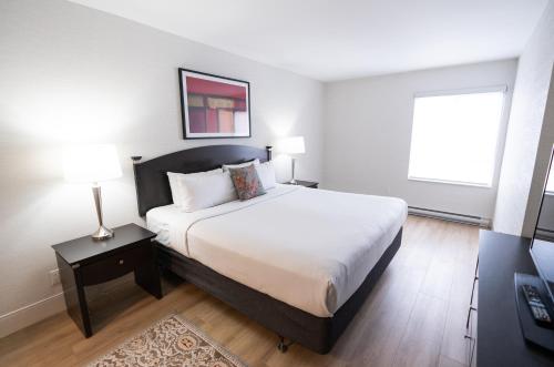 een slaapkamer met een groot bed en een raam bij Les Suites Hotel in Ottawa
