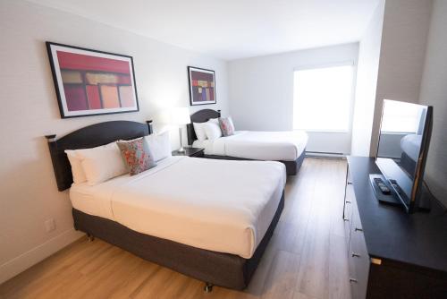 een hotelkamer met 2 bedden en een raam bij Les Suites Hotel in Ottawa