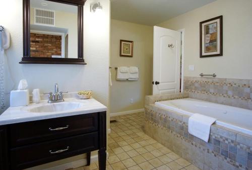 a bathroom with a tub and a sink and a mirror at Charm Motel & Suites in Burney