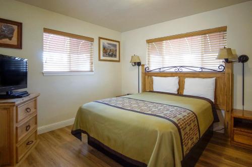 a bedroom with a bed and a flat screen tv at Charm Motel & Suites in Burney