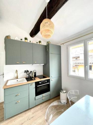 une cuisine avec des armoires bleues, un évier et une fenêtre dans l'établissement Ravissant appartement au cœur d’Aix, à Aix-en-Provence