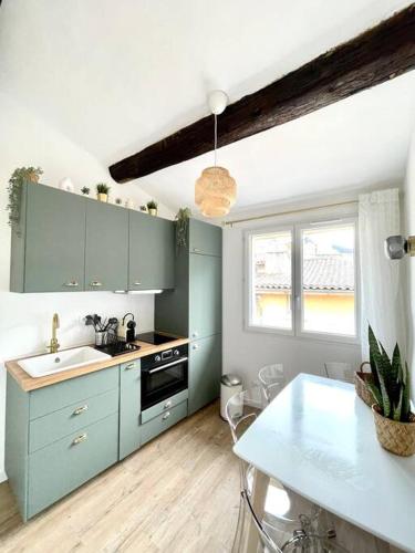 une cuisine avec des armoires bleues, un évier et une table dans l'établissement Ravissant appartement au cœur d’Aix, à Aix-en-Provence