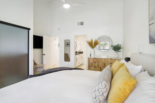 a bedroom with a large white bed with yellow pillows at Palm Desert Condo Country Club Perks and Pond Views in Palm Desert