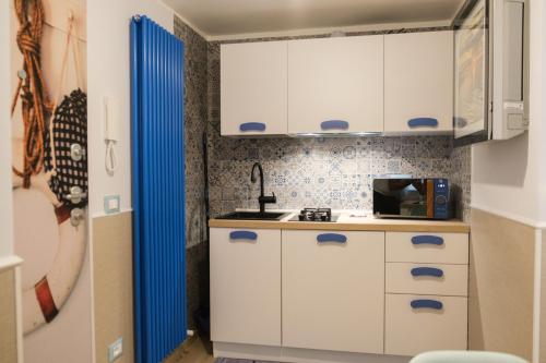 a small kitchen with white cabinets and blue accents at Appartamenti Vale Mare 2 in Chioggia