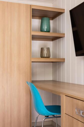 a blue chair sitting next to a desk and a television at Del Marcos Hotel in Palm Springs