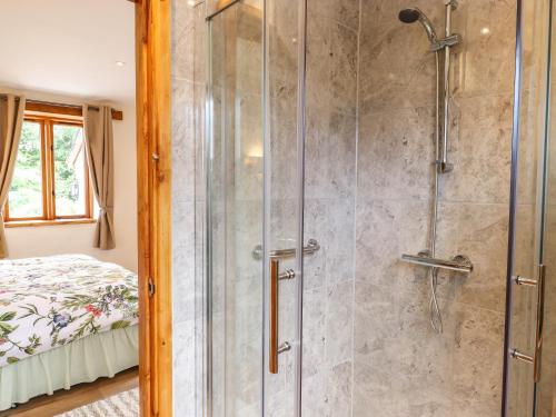 a bathroom with a shower with a glass door at Quoit X Barn in Tiverton