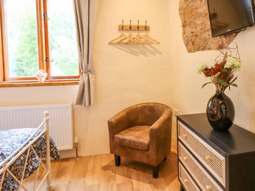 a bedroom with a chair and a tv on a dresser at Quoit X Barn in Tiverton