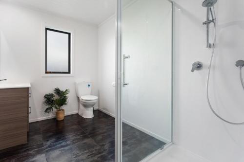 a bathroom with a glass shower and a toilet at Beach Bach on Boulevard in Opotiki