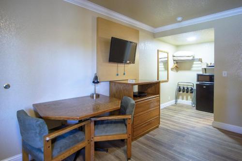 a dining room with a table and a tv on a wall at Charm Motel & Suites in Burney