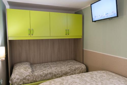a small room with two beds and green cabinets at Appartamenti Vale Mare 2 in Chioggia