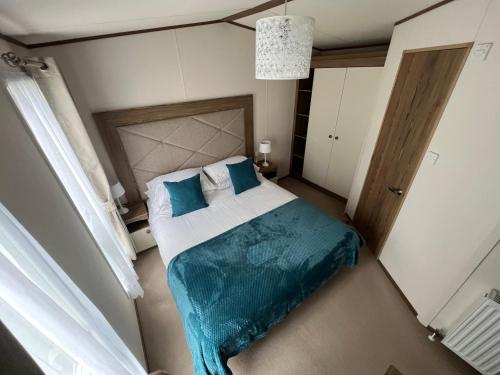 a bedroom with a large bed with blue sheets at Althea, White Horse, Seal Bay Resort in Selsey