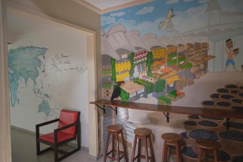a room with a mural on the wall and stools at Belem Hostel in Belém