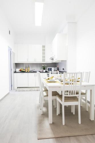 a white kitchen with a white table and chairs at Glamorous Apartment Park Ed VII in Lisbon