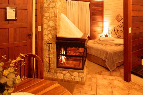 a bedroom with a fireplace in a room with a bed at Pousada Varanda das Colinas in Monte Verde